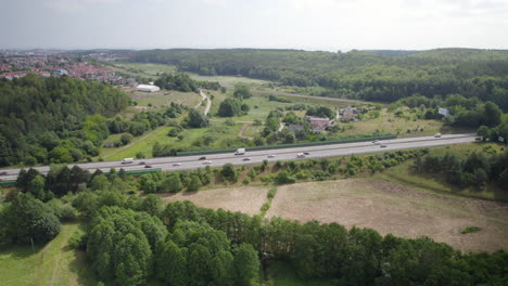 Autopista-Asfaltada-Con-Transporte-Terrestre-Acelerando-En-Carriles-A-Través-De-Paisajes-Verdes-En-Gdynia,-Polonia
