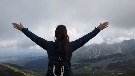 Cinematic-shot-of-a-woman-with-her-arms-outstretched-as-a-sign-of-freedom-and-amazed-at-the-wonderful-landscape-of-the-Tatra-Mountains-in-Poland