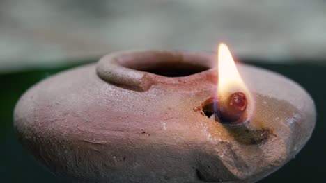 Middle-Eastern-vintage-handmade-clay-lamp-with-the-wick-lit---turning-isolated-close-up