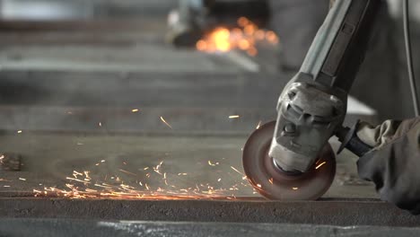 Blacksmith-grinding-metal-plates-with-circular-saw-in-metal-casting-factory,-closeup-slow-motion-shot-of-sparks-flying-from-hot-metal
