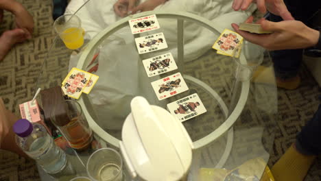 Gruppe-Von-Jugendlichen,-Die-Karten-Auf-Einem-Glastisch-In-Hongkong-Spielen