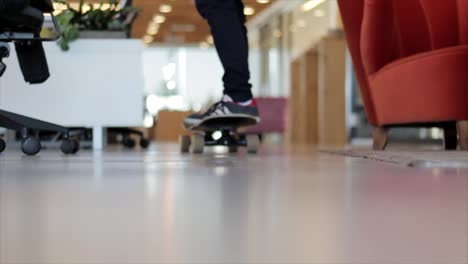 Der-Rebellische-Junge-Fährt-Drinnen-In-Einem-Büroraum-Skateboard,-Einfache-Und-Entspannte-Fahrt