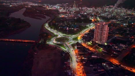 Aerial-panorama-view-of-Concón-at-night,-traffic-in-roundabout-with-oil-refinery-plant-as-background,-Chile
