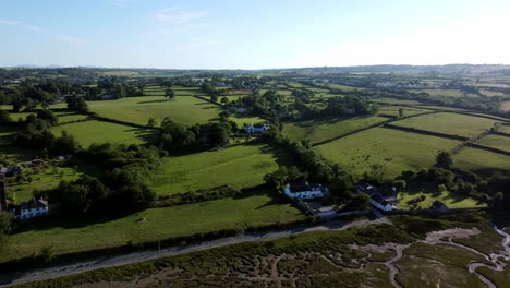 Aerial-view-orbiting-Traeth-Coch-Pentraeth-farmland-countryside-with-vacation-cottages-along-salt-marsh