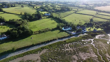Aerial-view-looking-down-Traeth-Coch-Pentraeth-farmland-countryside-with-vacation-cottages-along-salt-marsh