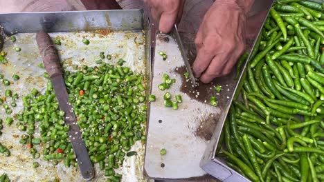 Close-up-shot-of-a-poor-man-chopping-green-chilies-on-roadside-Dhaba