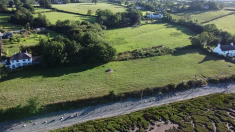 Aerial-view-Traeth-Coch-Pentraeth-farmland-countryside-with-vacation-cottages-along-salt-marsh-pan-left