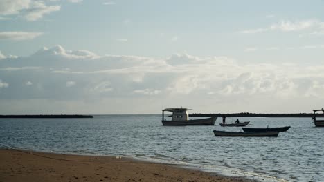 Fischer-Auf-Einem-Boot,-Der-An-Einem-Sonnigen-Tag-Mit-Booten-Am-Horizont-In-Zeitlupe-Fischfangnetze-Ins-Wasser-Wirft