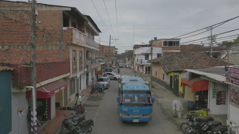 Aerial-flyover-of-a-street-in-Colombia-with-a-bus-slowly-passing-underneath