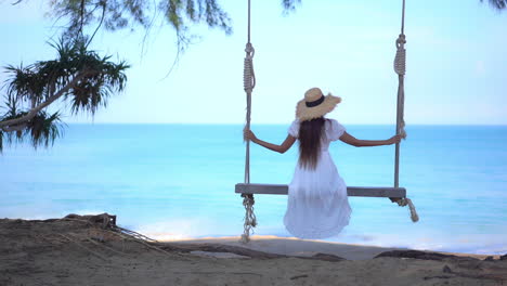 Back-of-Woman-in-White-Summer-Dress-on-Sing-Under-Tree-With-Stunning-View-of-Tropical-Sea