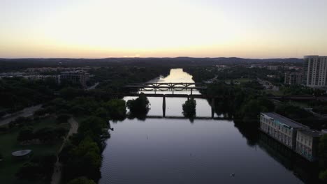 Aerial-view-towards-bridges-on-the-Colorado-river-in-Austin,-vibrant-dusk-in-Texas,-USA