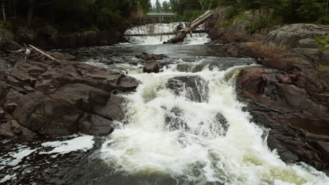 Drone-flying-low-over-fresh-water-cascade-in-Algonquin-park,-Ontario