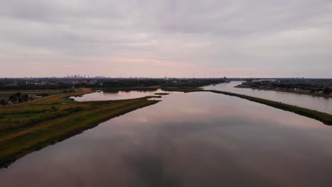 Aerial-Dolly-Left-Across-Calm-Reflective-Tranquil-Sunset-Over-River-Beside-Crezeepolder-Nature-Reserve