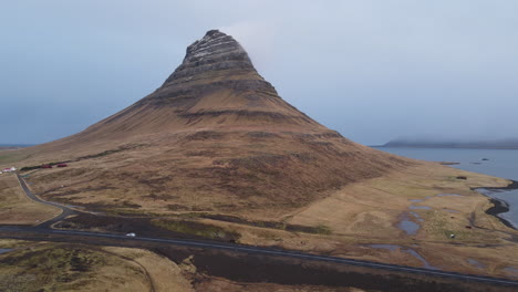 Aerial-shot-of-a-car-passing-on-Kirkjufell-road-in-Iceland