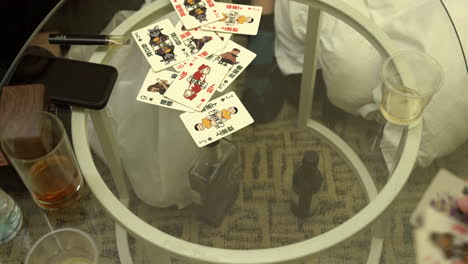 People-playing-a-typical-card-game-in-hong-kong,-on-a-glass-table
