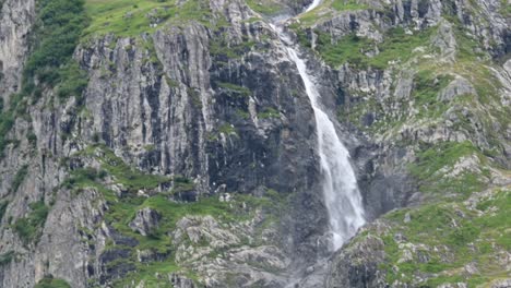 Vista-De-Una-Fachada-De-Roca-De-Una-Montaña-En-Los-Alpes-Suizos,-Engelberg,-Obwalden,-Un-Río-Fluye-A-Través-De-Las-Rocas