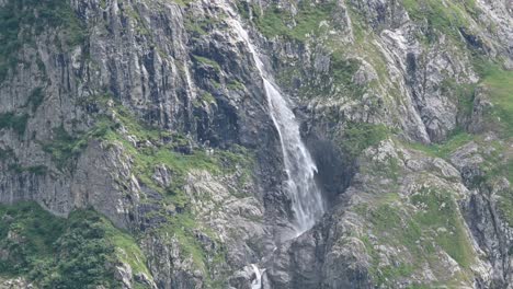 Wide-view-of-a-rocky-mountain-slope,-facade,-a-waterfall-flows-down-the-mountain