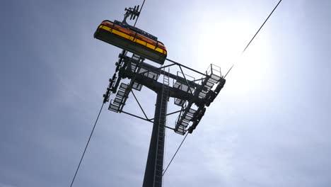Low-angle-camera-shot-looking-up-at-chairlift-cable-car-with-blue-sky