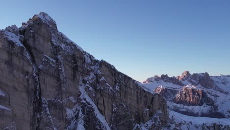 Soaring-past-Ra-Gusela-mountain-peak-revealing-stunning-winter-Dolomites,-sunset