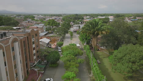 Aerial-footage-following-a-box-truck-driving-down-a-tree-covered-street-in-Jamundí,-Colombia