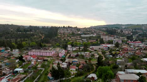 Dolly-in-aerial-view-of-a-sunset-in-a-lower-class-neighborhood-in-Quilpué,-Chile