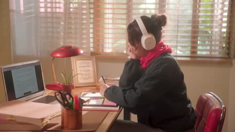 Teenager-Mädchen,-Das-Musik-Hört,-Während-Sie-Auf-Ihrem-Schreibtisch-Schreibt-Und-Lernt