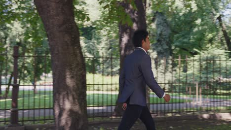 Business-sales-man-wearing-formal-clothes-walking-confidently-by-urban-park