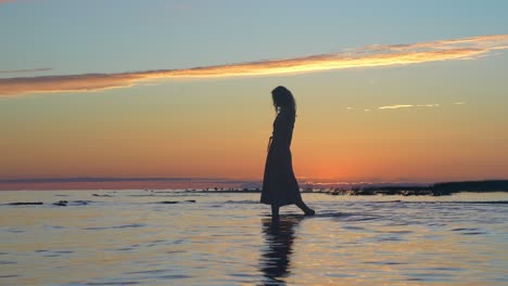 Attractive-woman-in-summer-dress-walking-on-shallow-sea-coastline