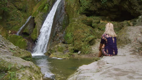 Beautiful-girl-with-blond-hair-is-daydreaming-in-front-of-the-waterfall
