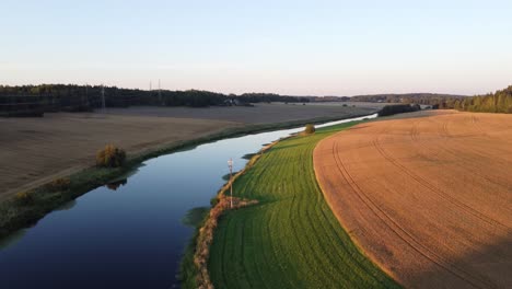 Small-river-surrounded-by-fields-during-the-sunset