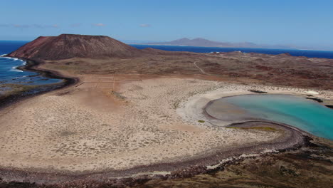 Aerial-shot-over-the-coast-and-the-beach-of-la-concha-on-the-island-of-wolves,-seeing-the-volcano-that-inhabits-it