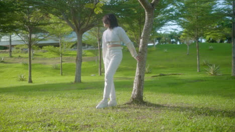 Woman-In-Long-Sleeve-Crop-Top-And-White-Ripped-Pants-Relaxing-And-Standing-Alone-In-The-Park