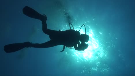 Silhouette-of-scuba-diver-against-the-sun-below-water-surface