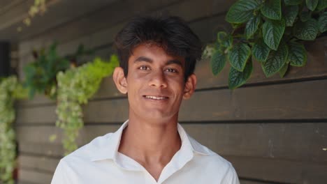 Porträt-Eines-Jungen-Indischen-Mannes,-Der-Im-Außengarten-Lächelnd-In-Die-Kamera-Blickt