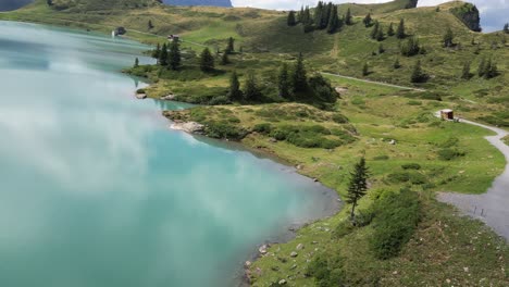 Vista-De-Drone-Fpv-De-Un-Lago-Alpino-Con-Agua-Azul-Brillante-En-Los-Alpes-Suizos,-Reflejo-De-Nubes-En-La-Superficie,-Obwalden,-Engelberg