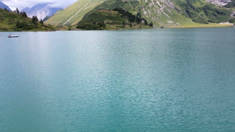 Tilt-up,-view-of-an-alpine-lake-with-clear-water-in-Obwalden,-drone-aerial-view,-mountains-and-tree-in-the-background