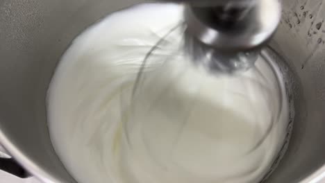 Preparation-of-fluffy-and-soft-Swiss-meringue-buttercream-pastry,-electric-mixer-mixing-and-beating-egg-white-and-sugar-until-it-is-glossy-peak-and-stiff-peak,-close-up-shot