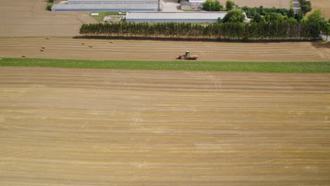 Wheat-Field-With-Working-Machinery-During-Harvest---aerial-drone-shot