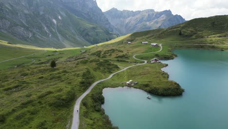 Push-in:-drone-aerial-view-of-an-alpine-lake's-shore-and-a-sinuous-path-for-people-to-admire-the-view,-rocky-mountains-in-the-background,-obwalden,-Engelberg