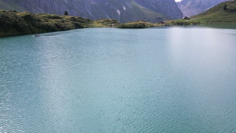 Tilt-up:-drone-aerial-view-of-an-alpine-lake-with-mountains-behind-in-the-swiss-alps-in-Obwalden,-Engelberg
