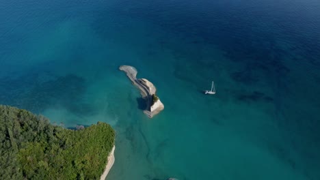 Sail-boat-moored-in-Greece-paradise-aerial-view-of-forest-coastline-with-tropical-natural-beach