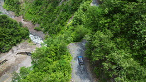 View-From-An-Above-Of-A-Nissan-Xterra-Driving-On-Steep-And-Narrow-Mountain-Road-With-Lush-Foliage-In-Tusheti,-Georgia