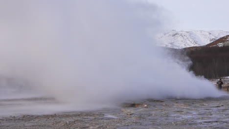 Tourist-watching-Strokkur-Geysir-in-Iceland-during-winter