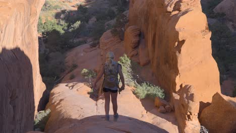 Joven-Mujer-Rubia-Caminando-Por-Una-Formación-Rocosa-Suave-En-El-Parque-Nacional-Arches,-Utah