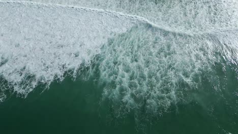 Long-aerial-top-down-of-powerful-ocean-waves-crashing-at-the-beach