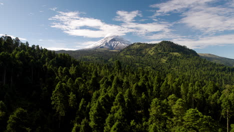Drone-shot-showing-the-snowy-top-of-the-popocatepetl-volcano-in-mexico-city-and-the-lush-forests-that-surround-it