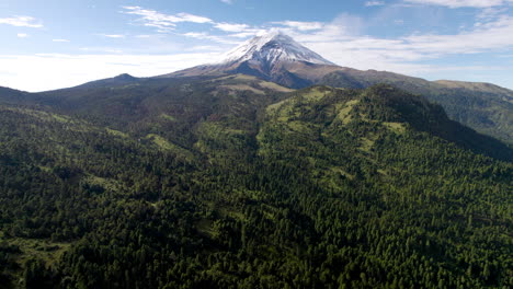 Tiro-De-Drones-Con-Vista-Hacia-Abajo-Durante-La-Mañana,-Con-Una-Vista-Panorámica-Del-Pico-Nevado-Del-Volcán-Popocatepetl-En-La-Ciudad-De-México