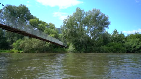 Drone-shot-flying-under-bridge-on-river-on-sunny-summer-day,-Slovakia