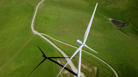 Aerial-view-over-a-wind-power-turbine-and-summer-green-field---reverse,-drone-shot