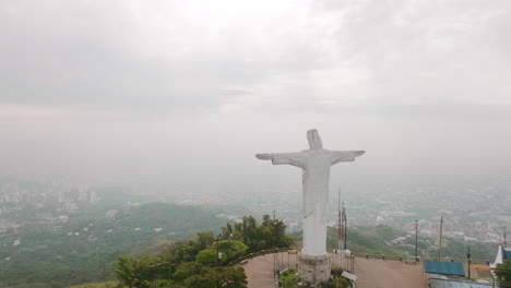 Slow-aerial-flyover-footage-of-the-Cristo-Rey-statue-that-flies-right-past-the-head-of-the-statue-in-the-city-of-Cali,-Colombia